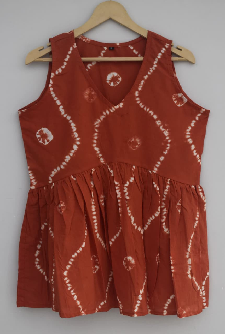 Rust or terracotta reddish-brown, tie-dye or Bandhani pattern, cotton sleeveless peplum top.